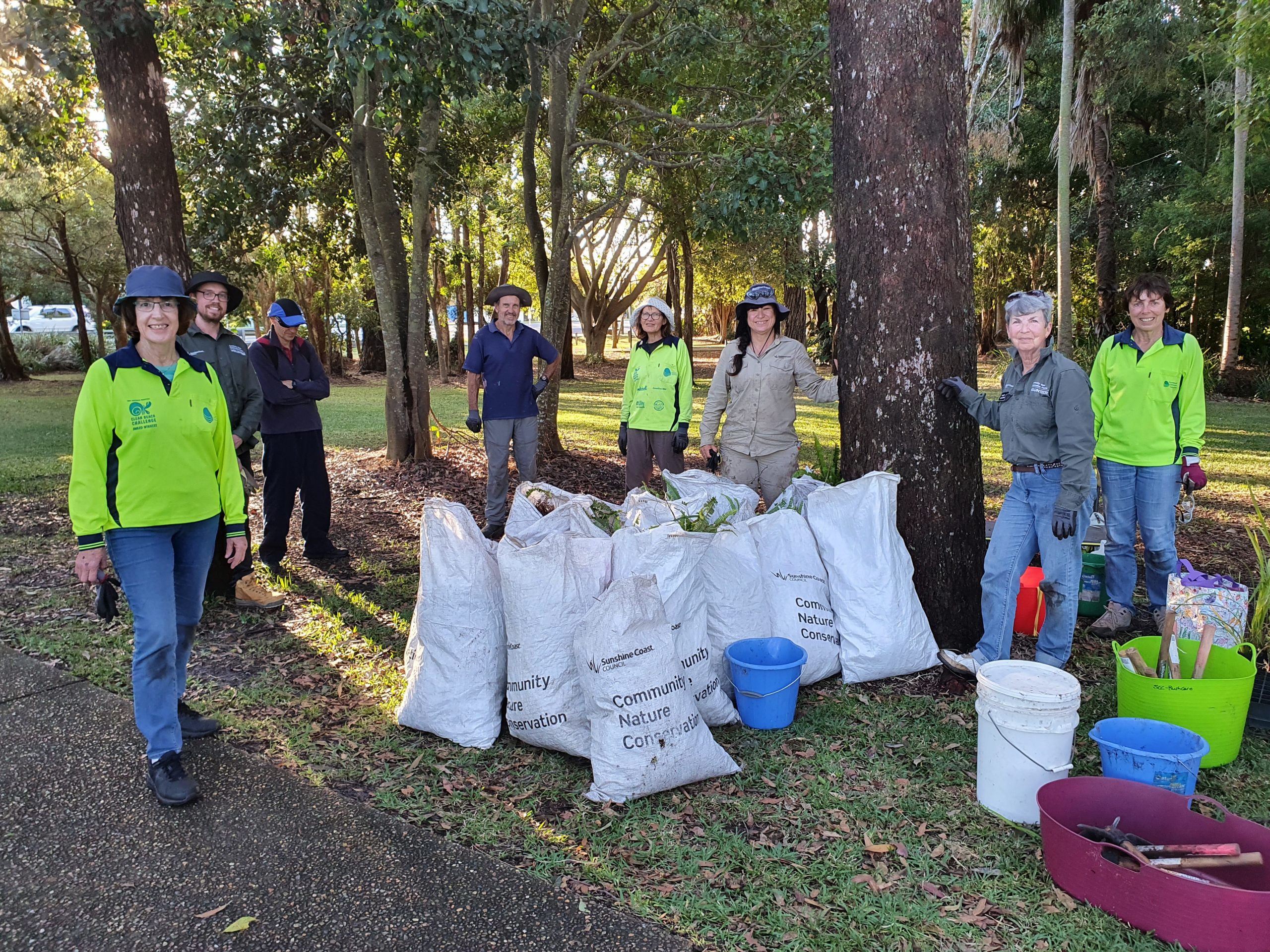 Image of working bee group posed with bags of weeds